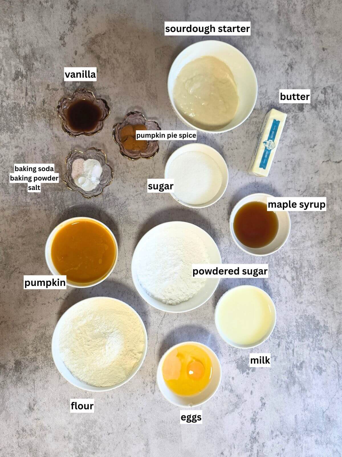 Ingredients for baked pumpkin donuts with maple glaze arranged in bowls.