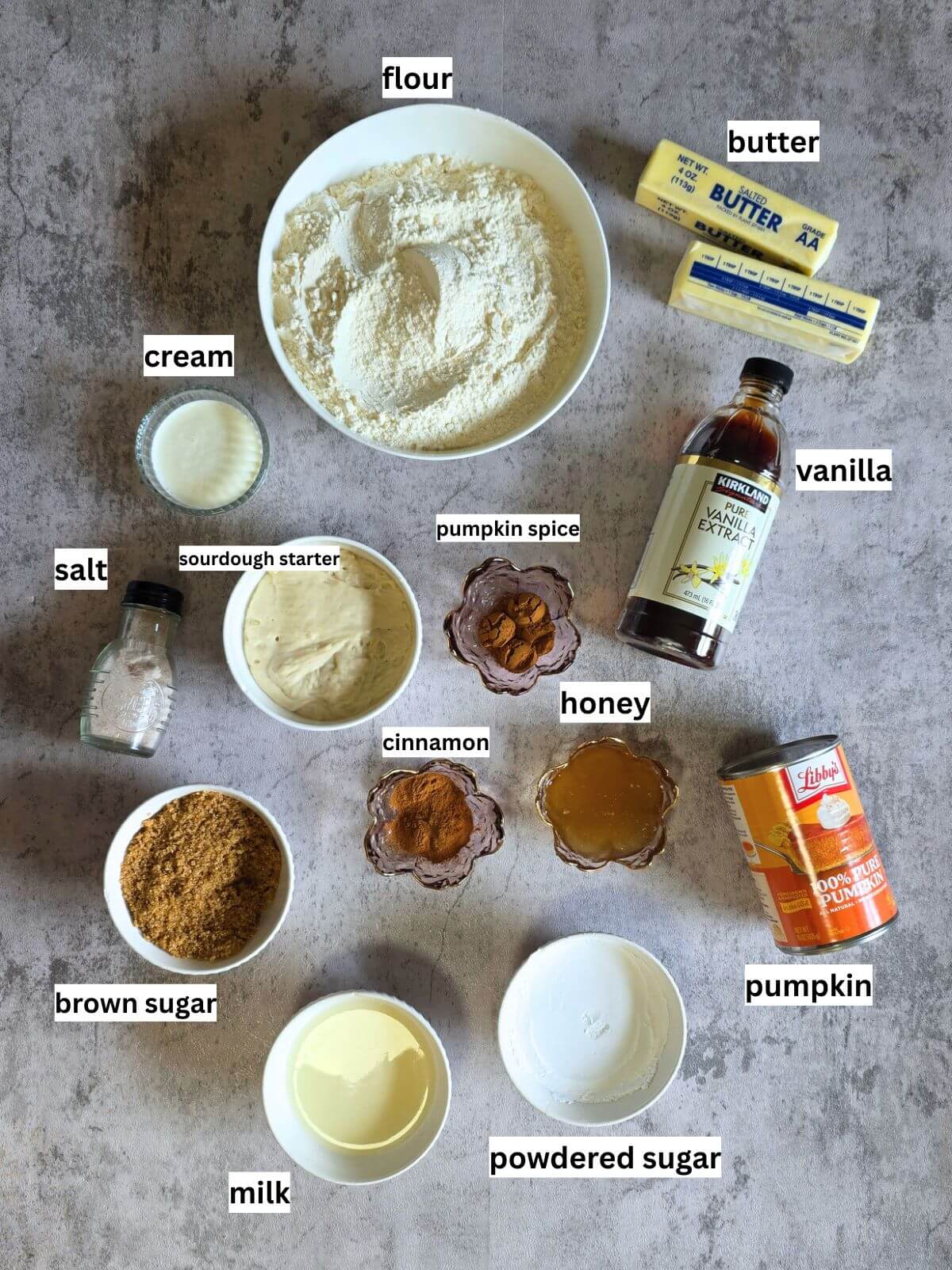 Ingredients for sourdough pumpkin cinnamon rolls including pumpkin, sourdough starter, flour, butter, brown sugar and spices.