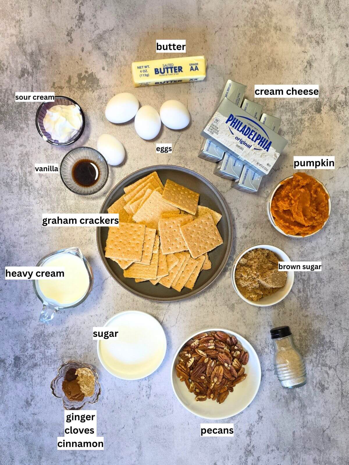 Ingredients for pumpkin cheesecake with caramel pecan topping arranged on a countertop.