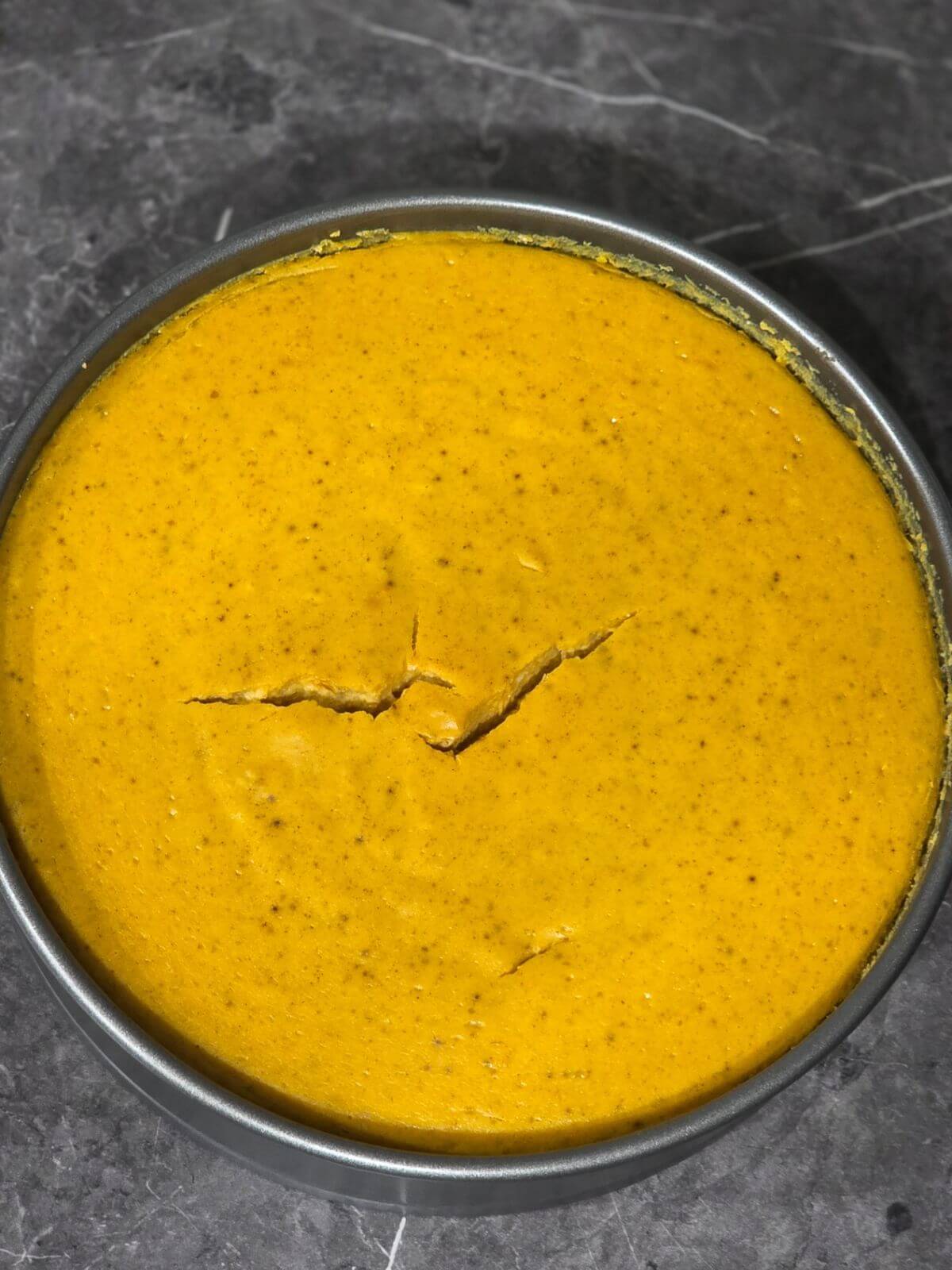 Baked pumpkin cheesecake cooling in a springform pan before chilling.