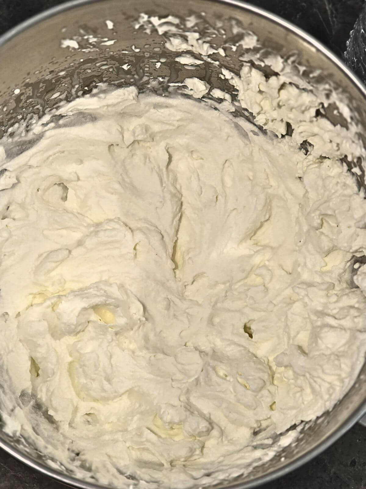 Freshly whipped cream beaten to stiff peaks for decorating pumpkin cheesecake.