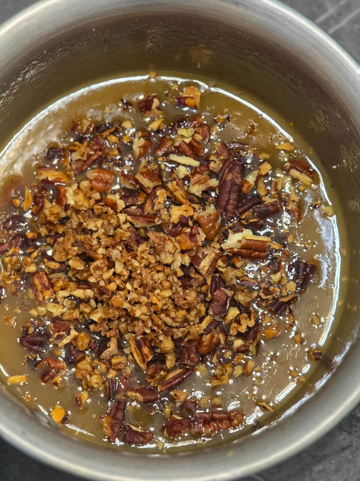 Homemade caramel pecan topping with toasted pecans in a saucepan.