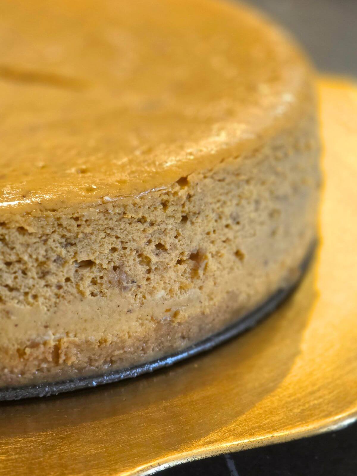 Close up of chilled pumpkin cheesecake showing the creamy spiced filling and graham cracker crust.