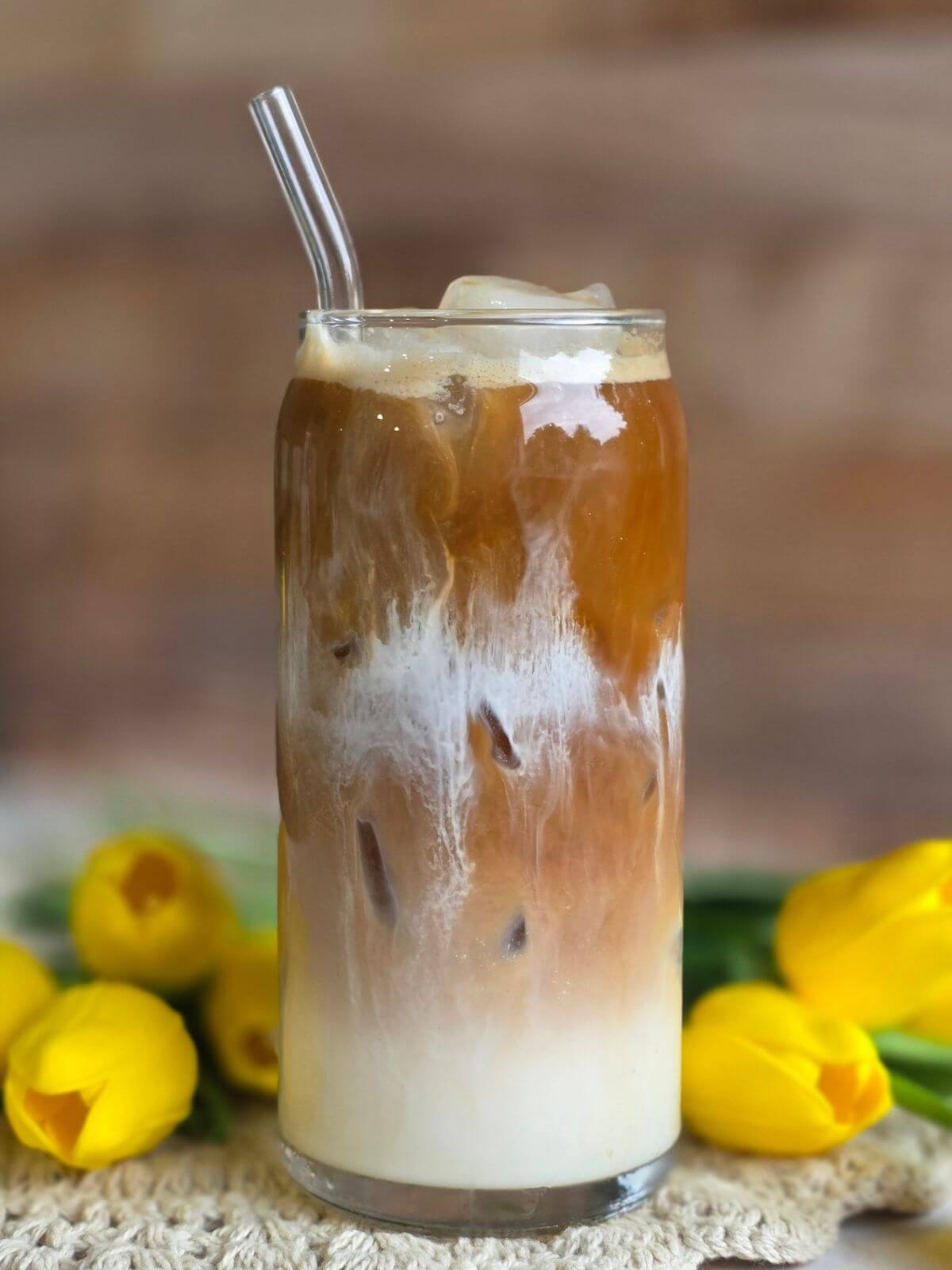 Layered maple iced coffee with espresso poured over cold milk, cream and ice.