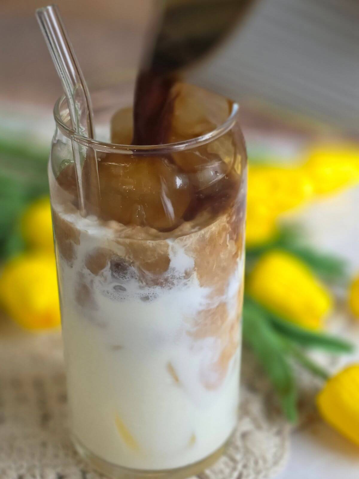 Maple sweetened espresso being poured over milk and ice to make an iced maple coffee.