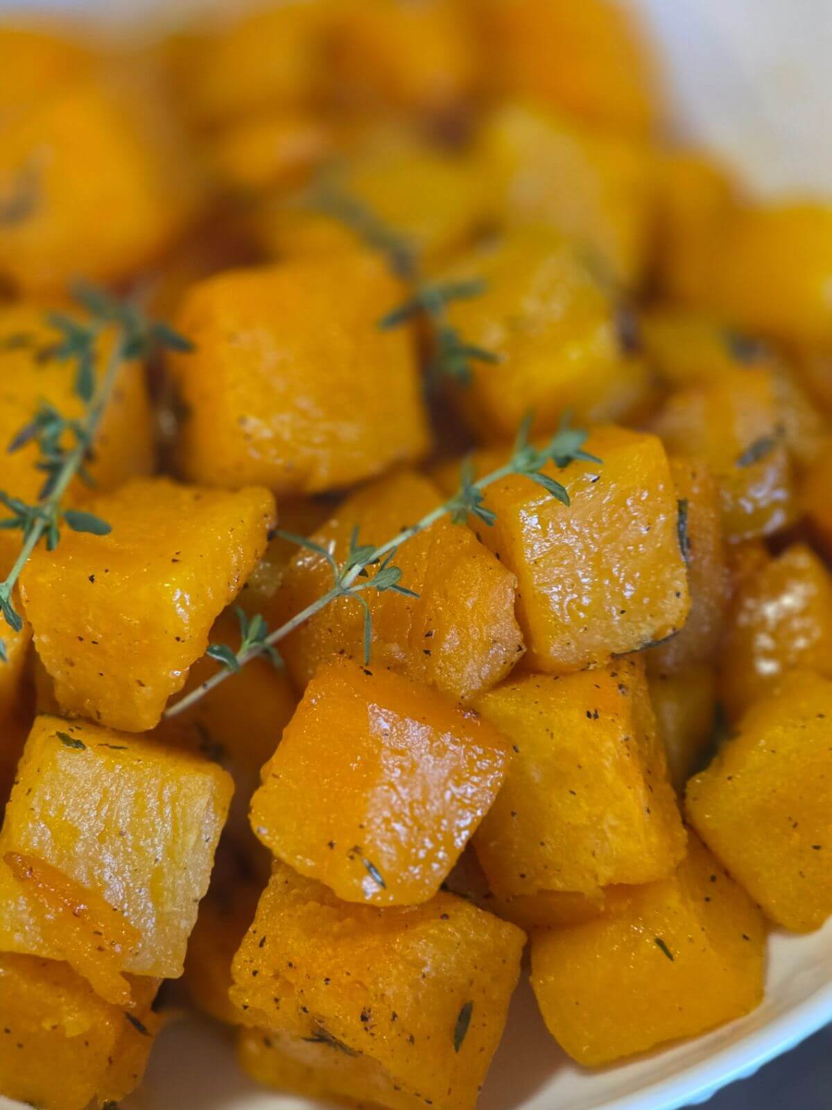 Close up of maple roasted butternut squash cubes with thyme.