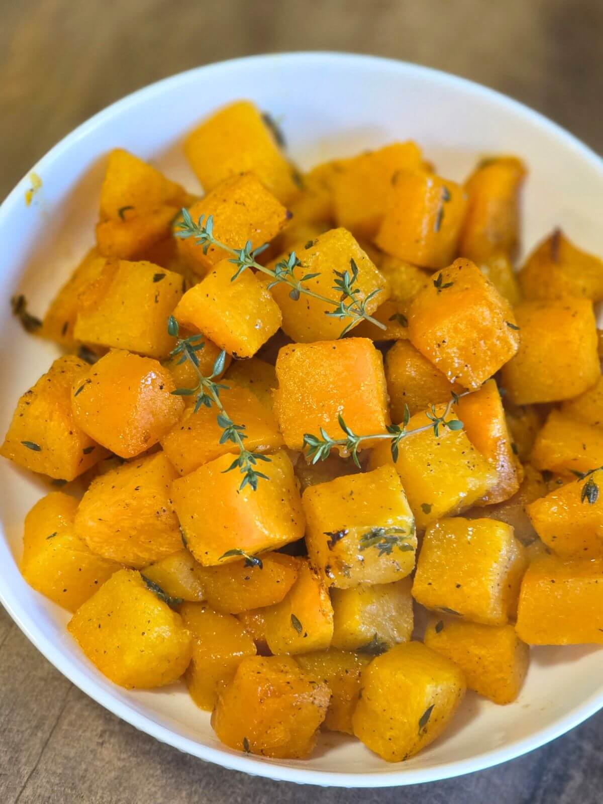 Close up of maple roasted butternut squash cubes with thyme.