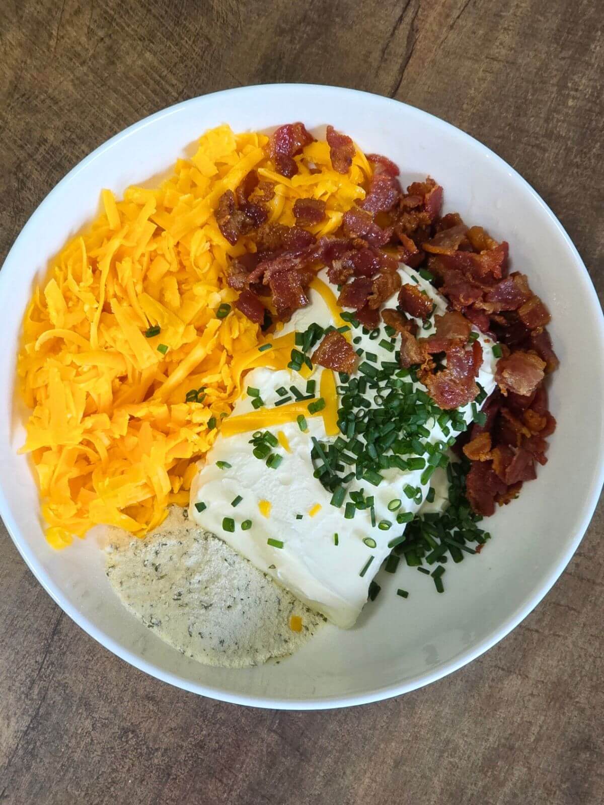 Cream cheese jalapeño popper filling with cheddar cheese, bacon, ranch seasoning, and chives in a bowl.