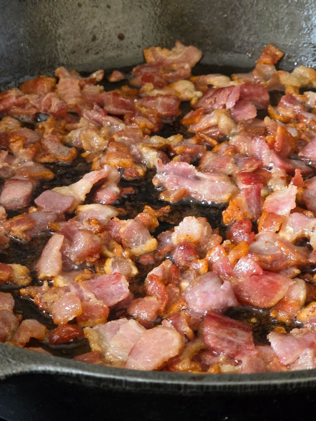 Chopped bacon cooking in a skillet for cream cheese jalapeño poppers.