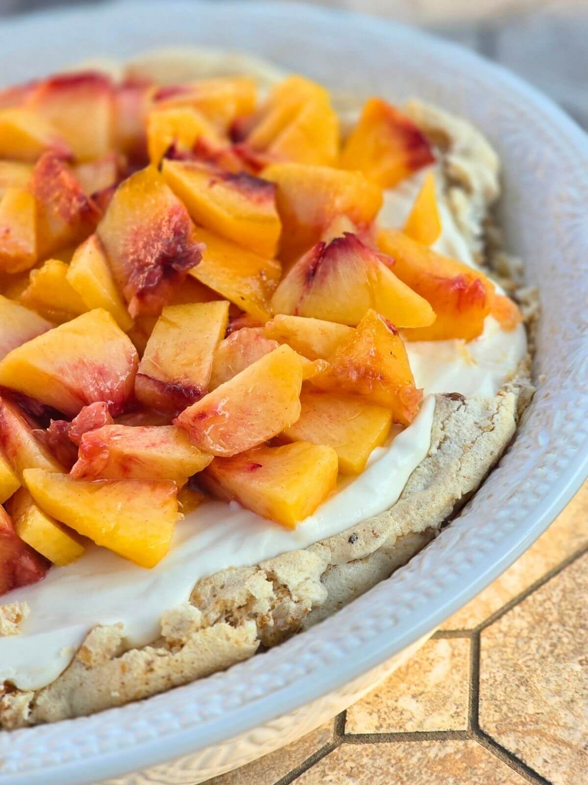 Fresh peach pie topped with juicy peaches over creamy filling.