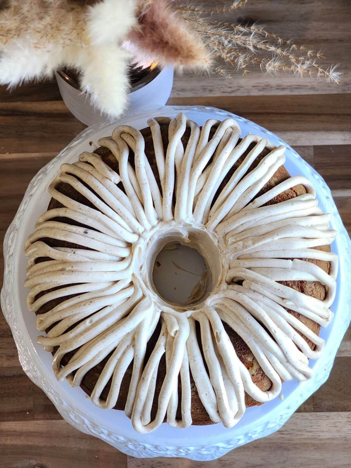 Pumpkin spice Bundt cake topped with piped cream cheese frosting, viewed from above.