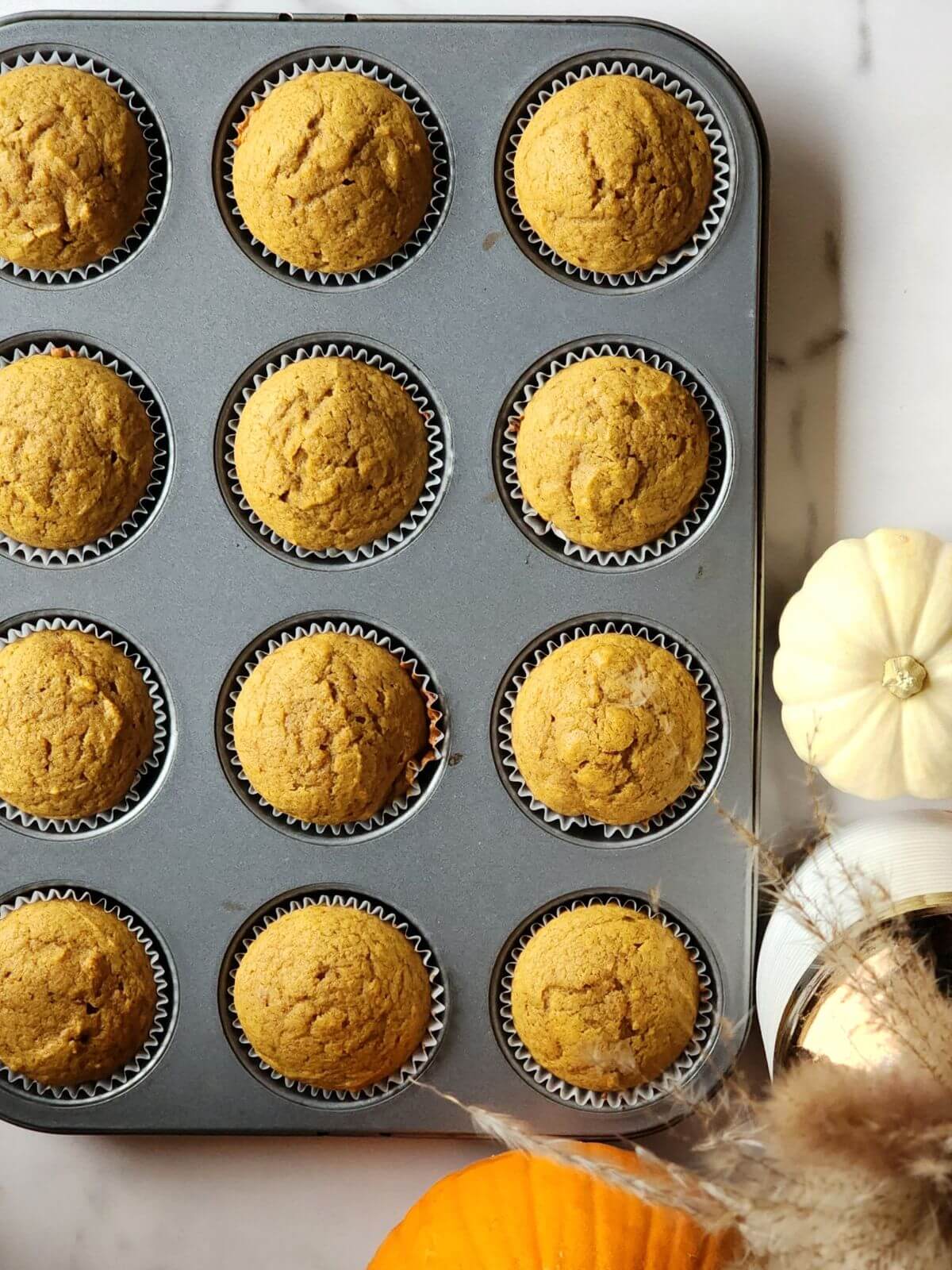 Freshly baked pumpkin spice cupcakes cooling in a muffin pan.