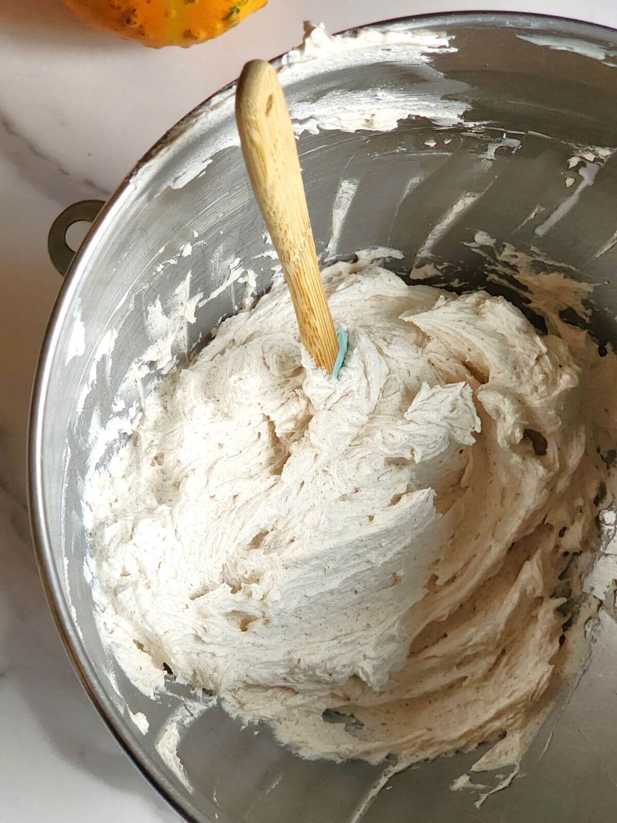 Fluffy cinnamon buttercream in the bowl of a stand mixer.
