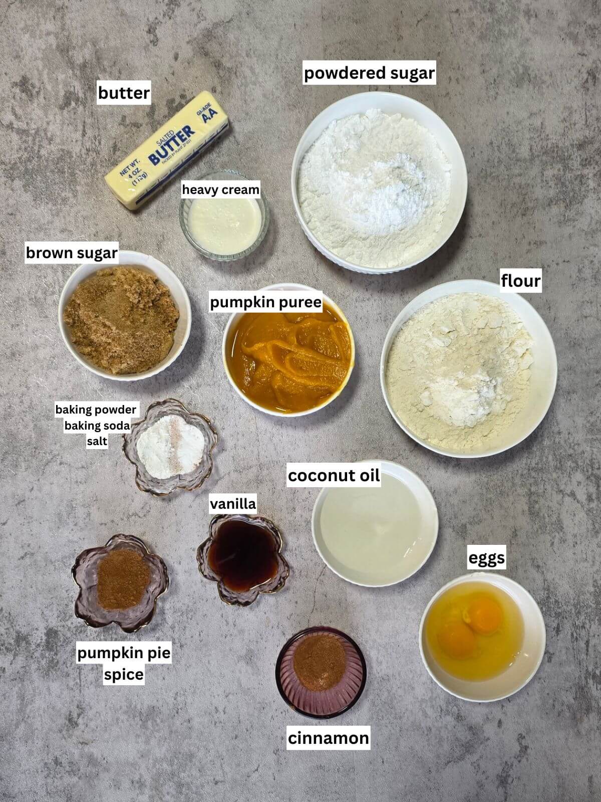 Ingredients for pumpkin spice cupcakes and cinnamon buttercream arranged in bowls and labeled.
