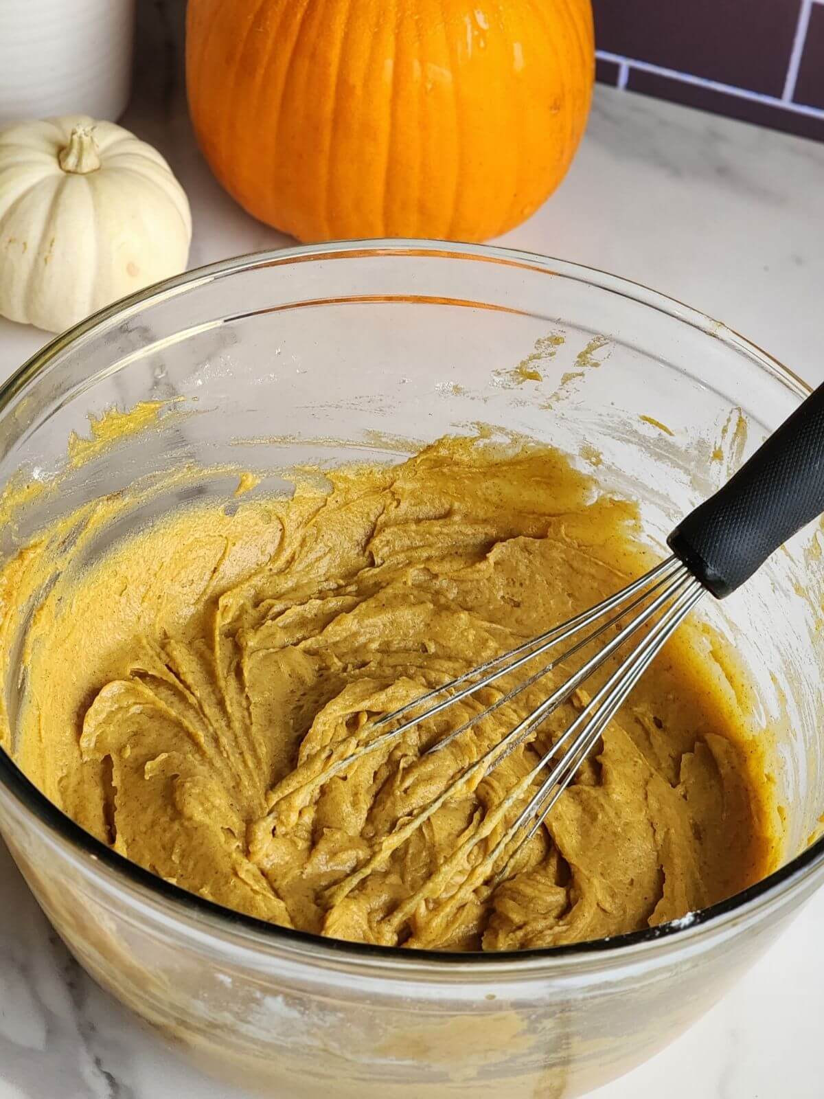 Thick pumpkin spice cupcake batter mixed in a large glass bowl.