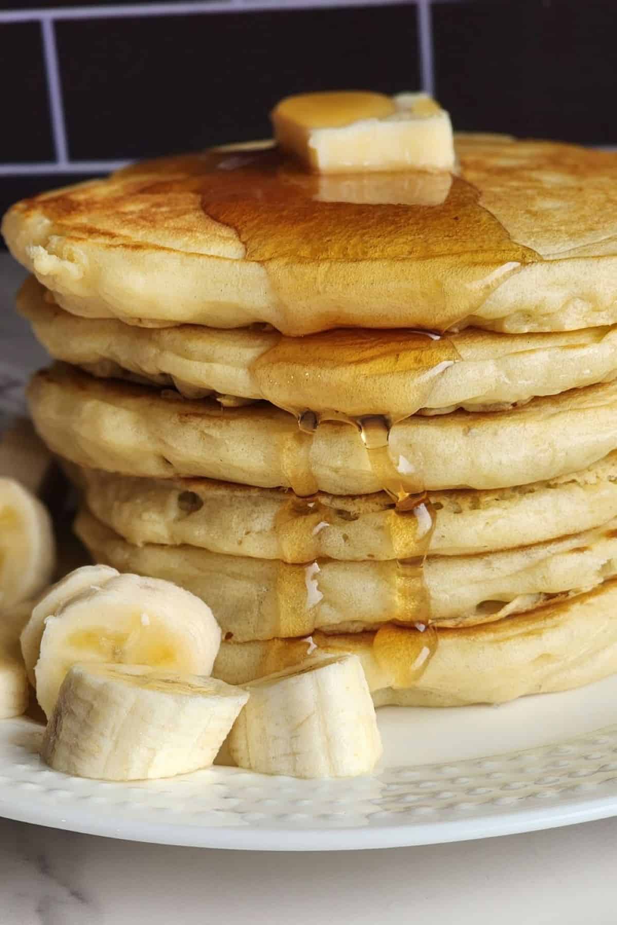 Stack of overnight sourdough pancakes with syrup running down the sides. 
