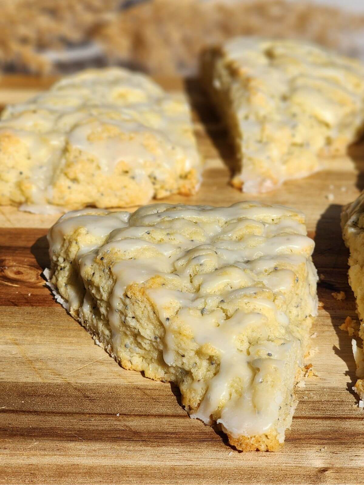 Almond poppy seed scone with almond glaze on a wooden board.
