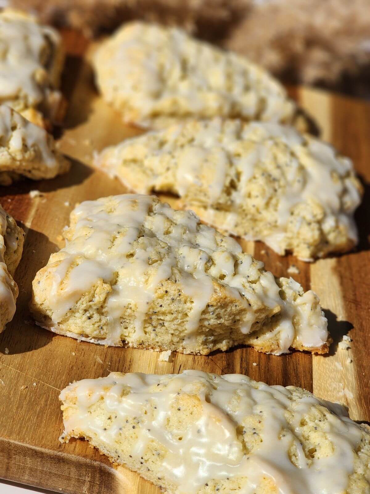 Almond poppy seed scone with almond glaze on a wooden board.