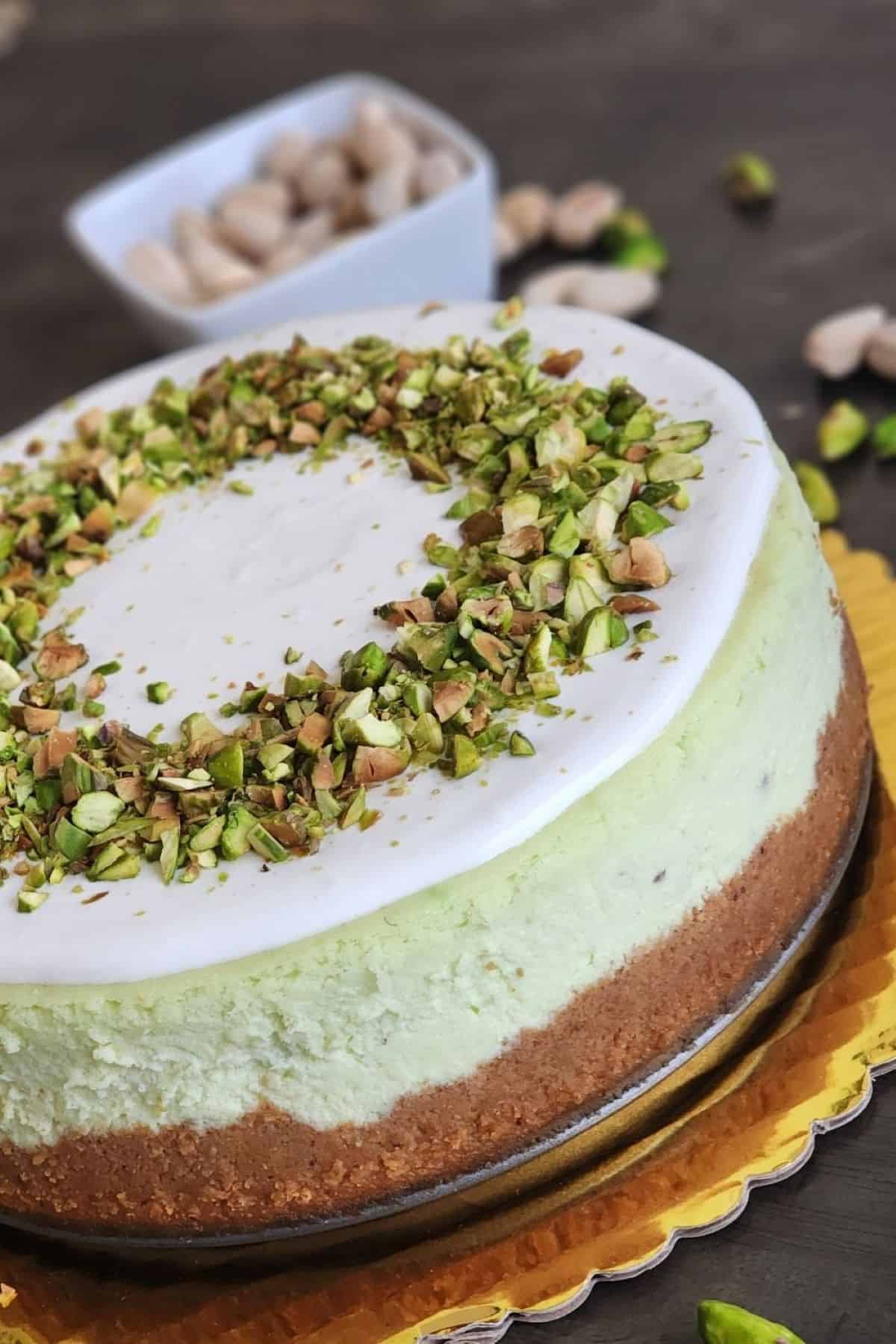 Pistachio cheesecake with sour cream icing and chopped pistachios.