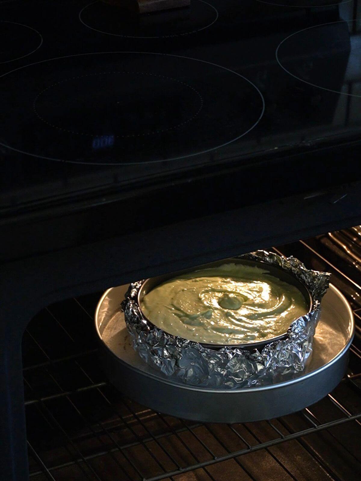 Pistachio cheesecake baking in a water bath in the oven.