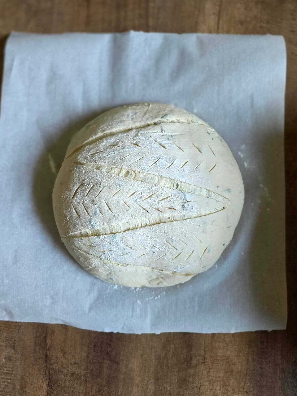 Scored roasted garlic and rosemary sourdough bread dough before baking.