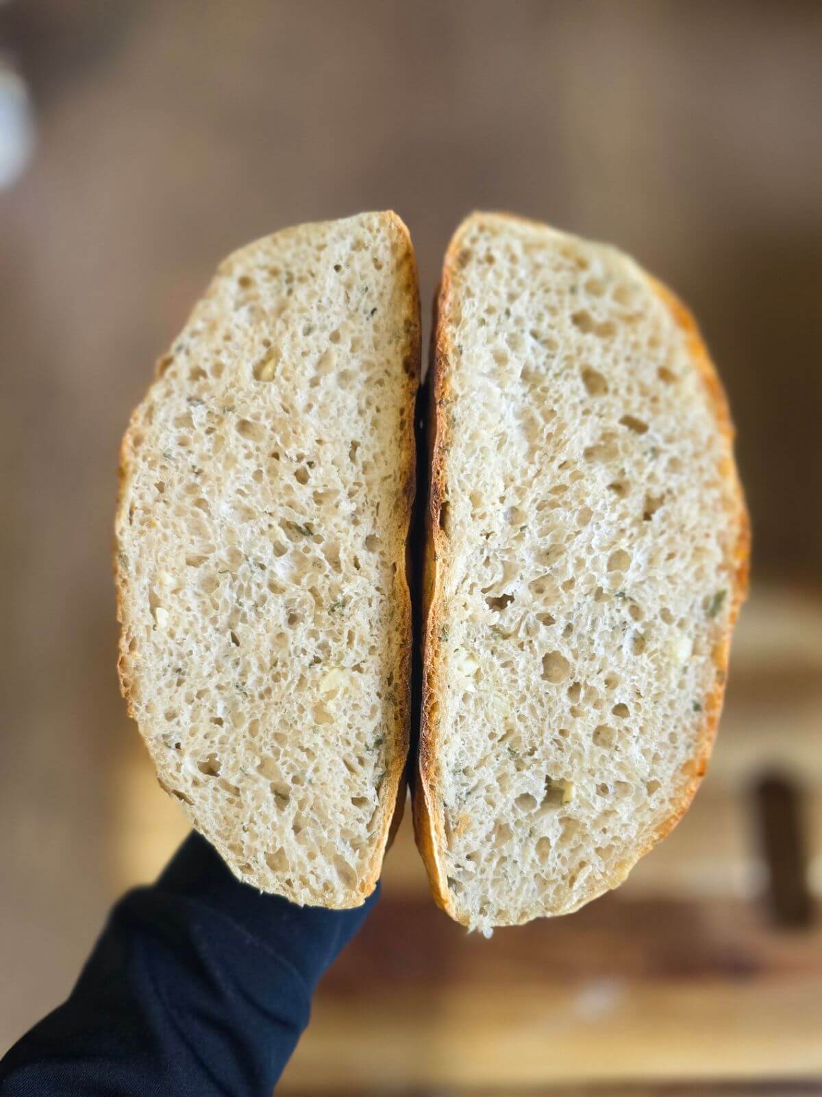 Sliced roasted garlic and rosemary sourdough bread showing the airy crumb with pieces of garlic and rosemary.