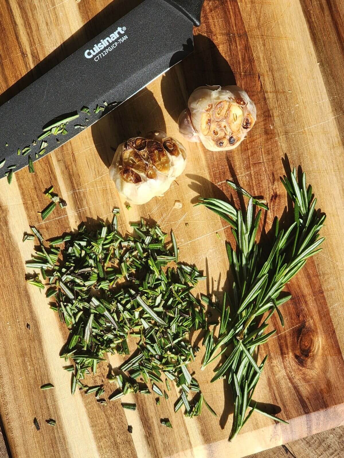 Fresh rosemary and roasted garlic on a cutting board for roasted garlic and rosemary sourdough bread.