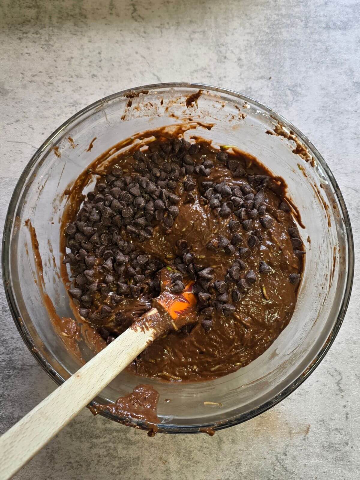 Chocolate chips being folded into sourdough zucchini brownie batter.