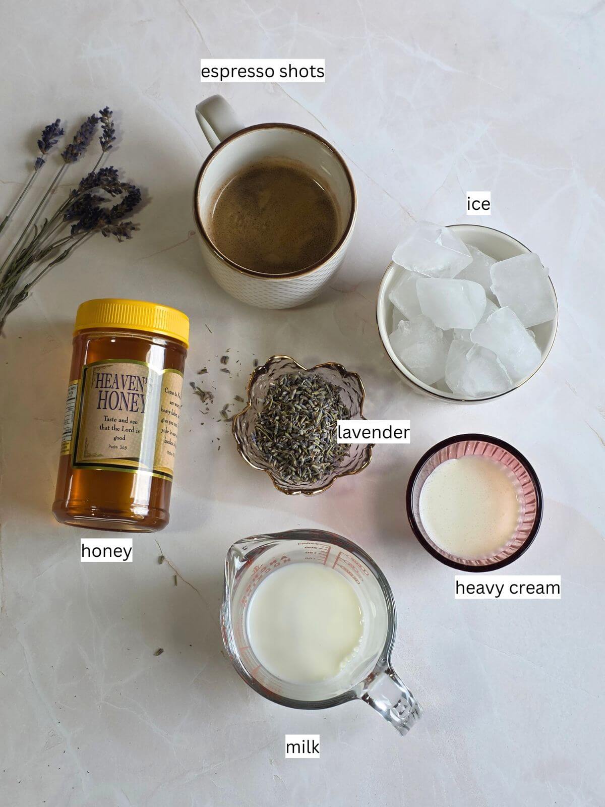 Ingredients for an iced honey lavender latte, including espresso, honey, culinary lavender, milk, heavy cream, and ice.