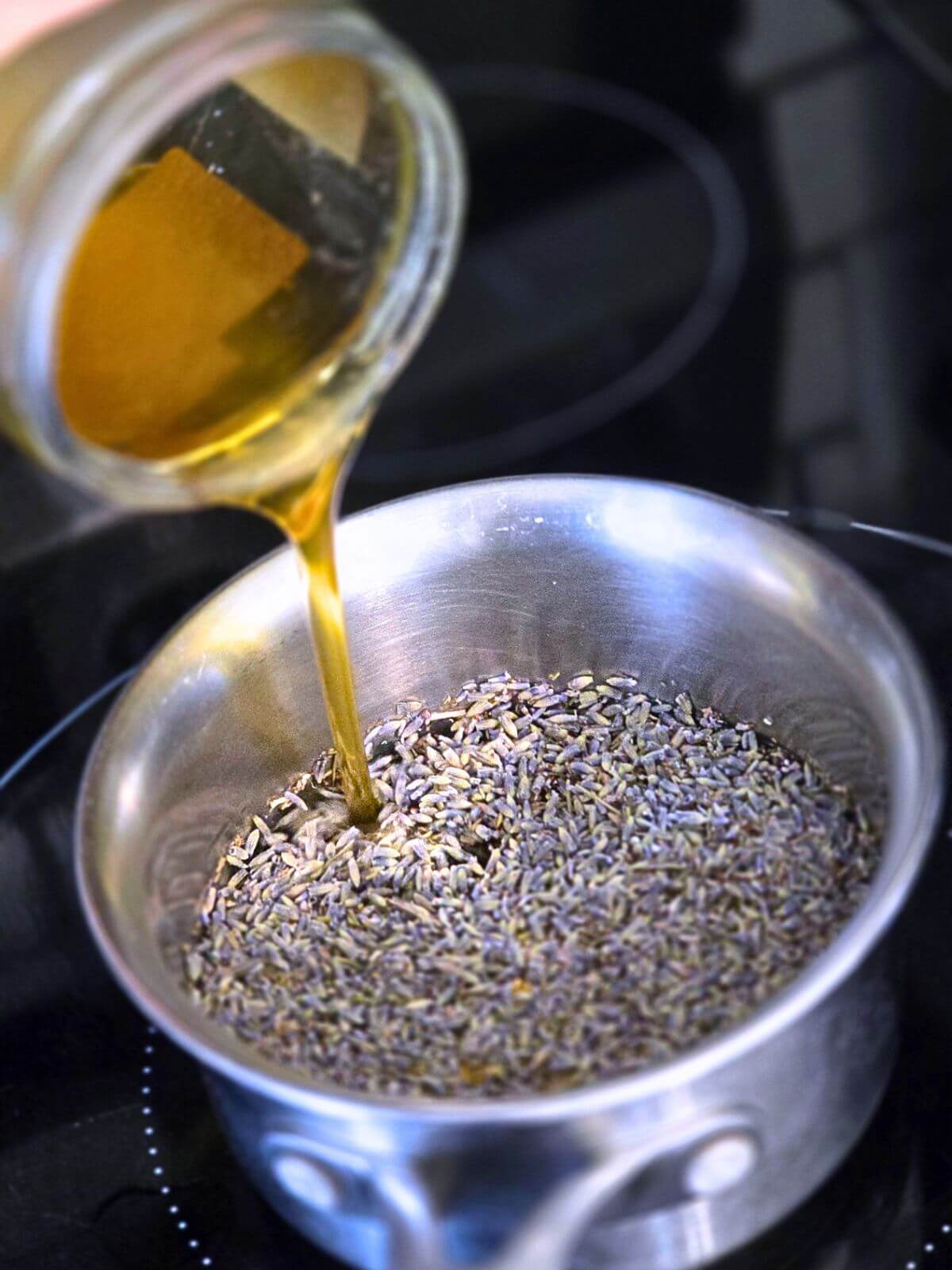 Honey being poured over dried culinary lavender in a saucepan to make honey lavender syrup.