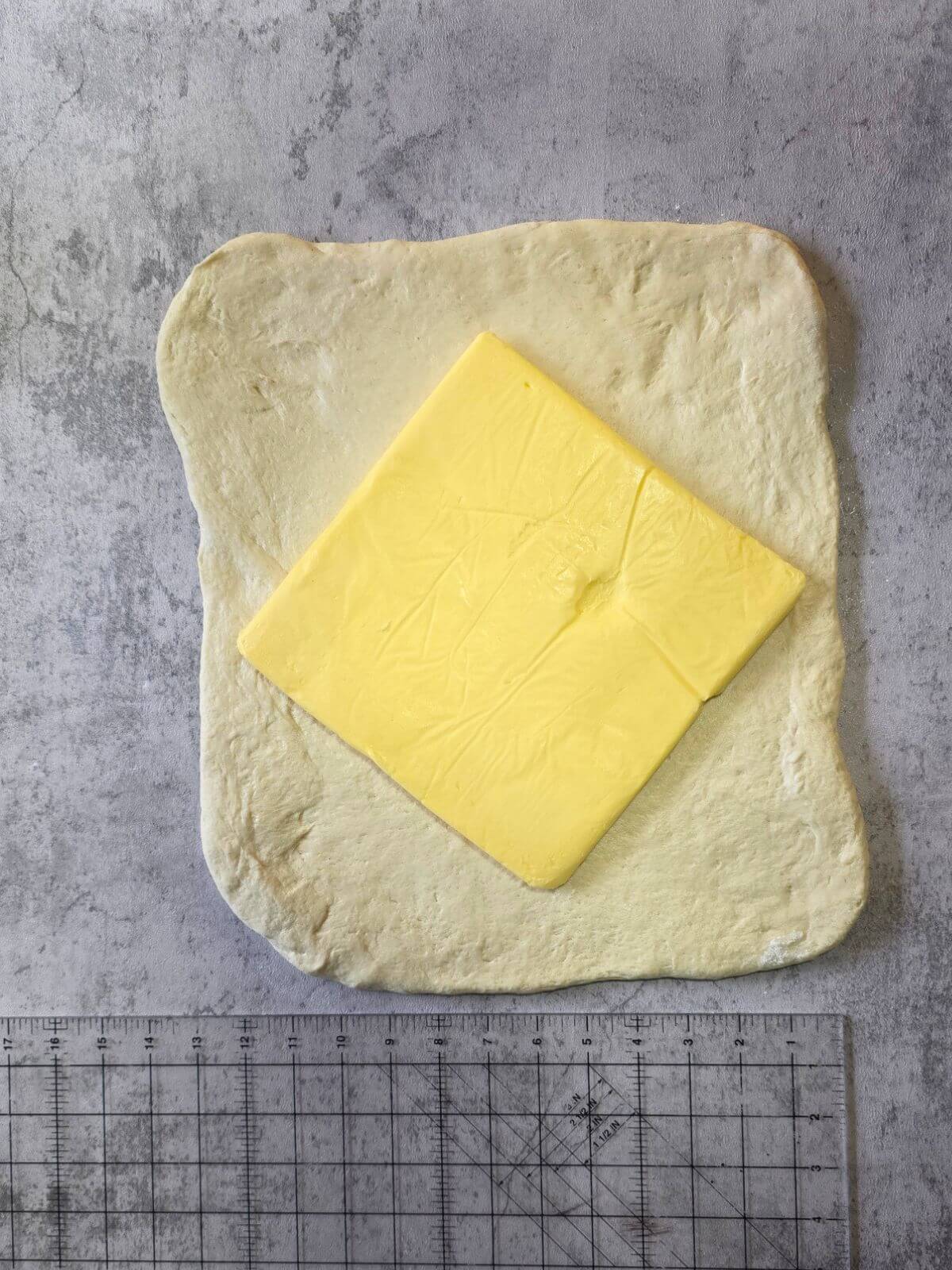 Cold butter block placed in the center of rolled sourdough croissant dough.