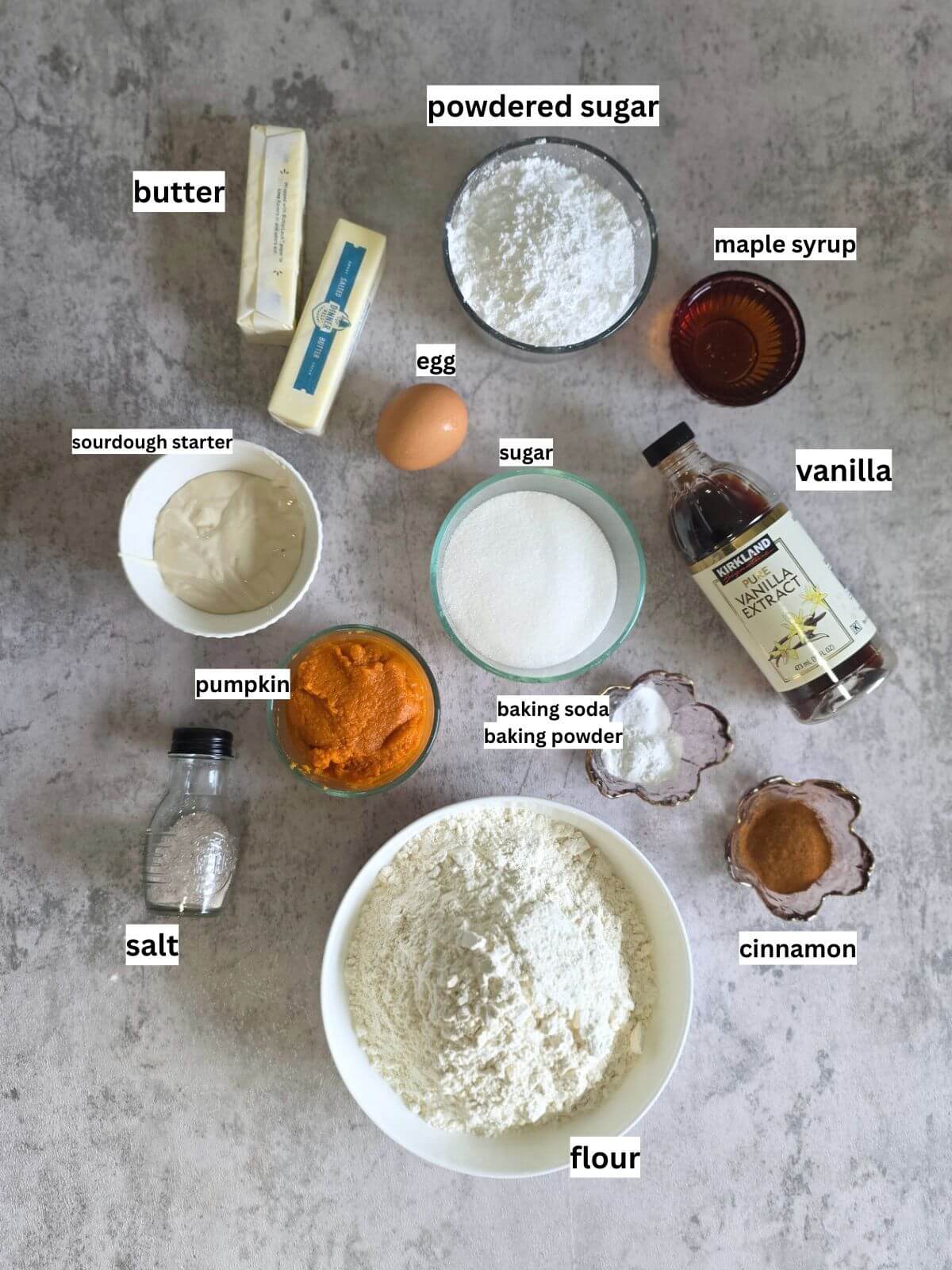 Ingredients for pumpkin sourdough scones with maple glaze arranged on a gray surface.