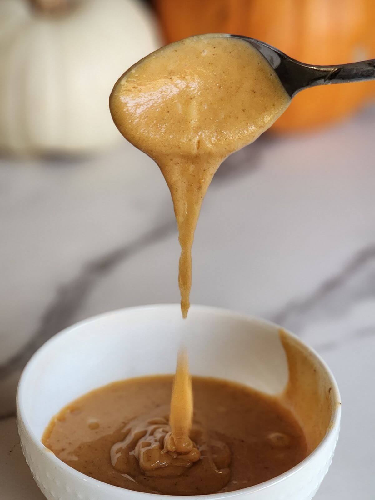 Maple glaze dripping from a spoon over a bowl.