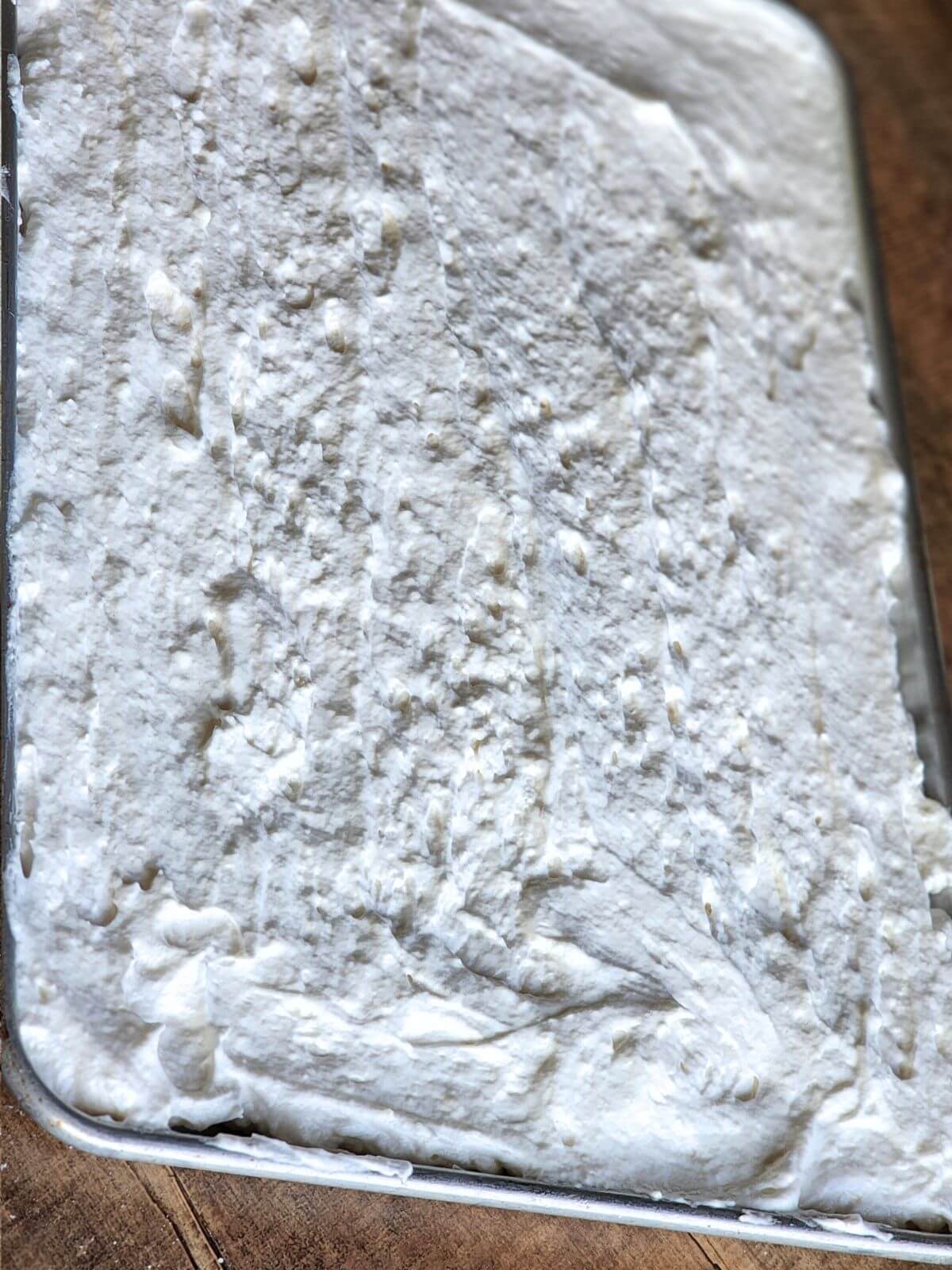 Angel food cake roll batter spread into a parchment lined jelly roll pan.