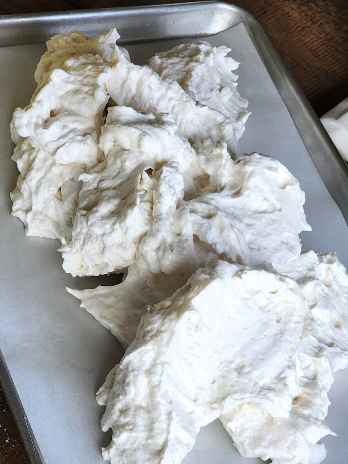 Angel food cake batter spooned onto a parchment lined jelly roll pan for a cake roll.