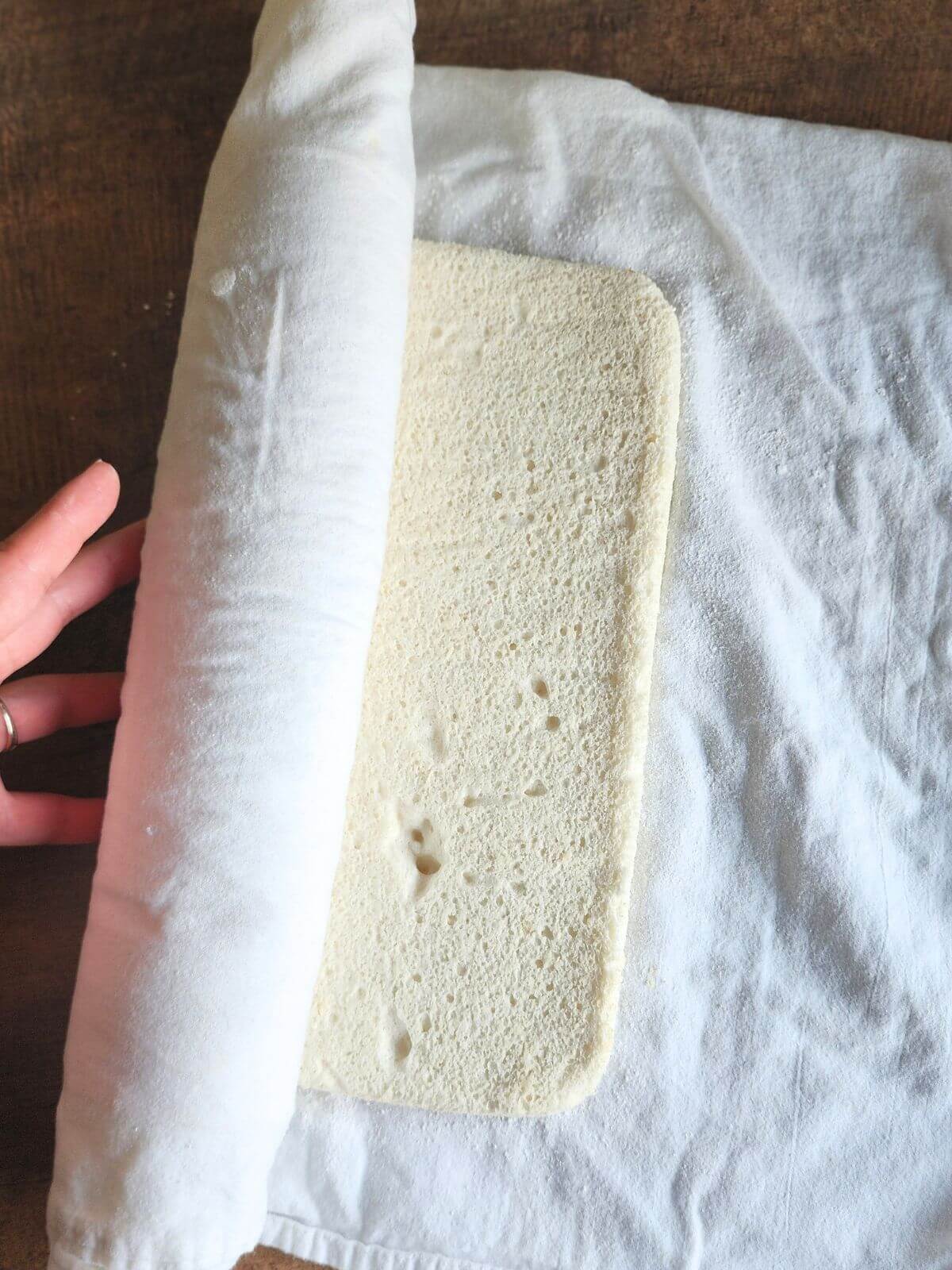 Angel Roll Cake getting rolled up with a towel.