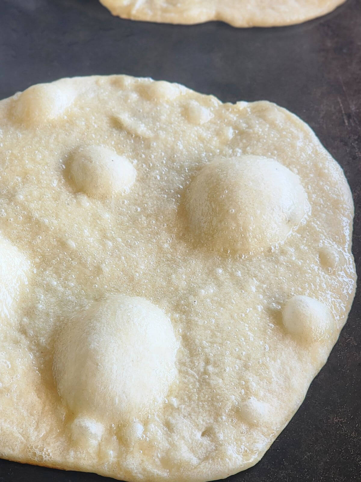 A bubbling piece of naan bread cooking.