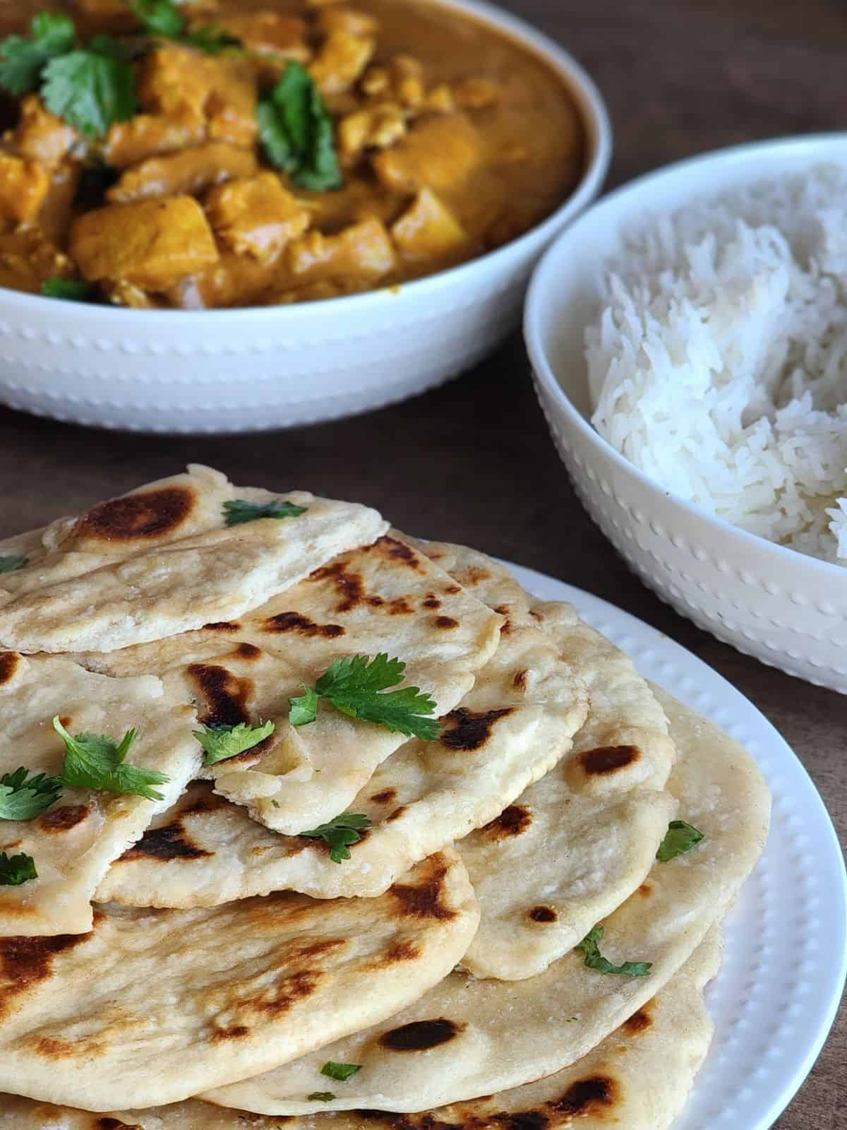 A meal with butter chicken, rice and naan.