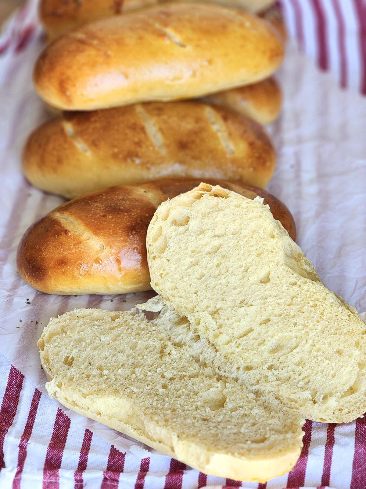 Soft golden hoagie rolls with one cut open to see the crumb. 