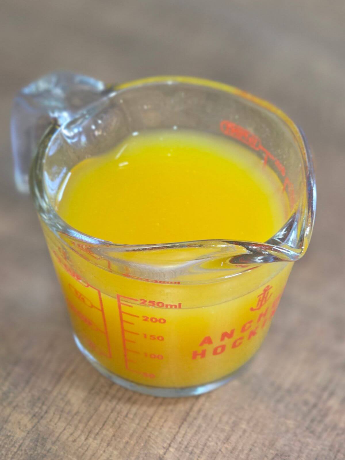 Homemade mango syrup in a measuring cup.