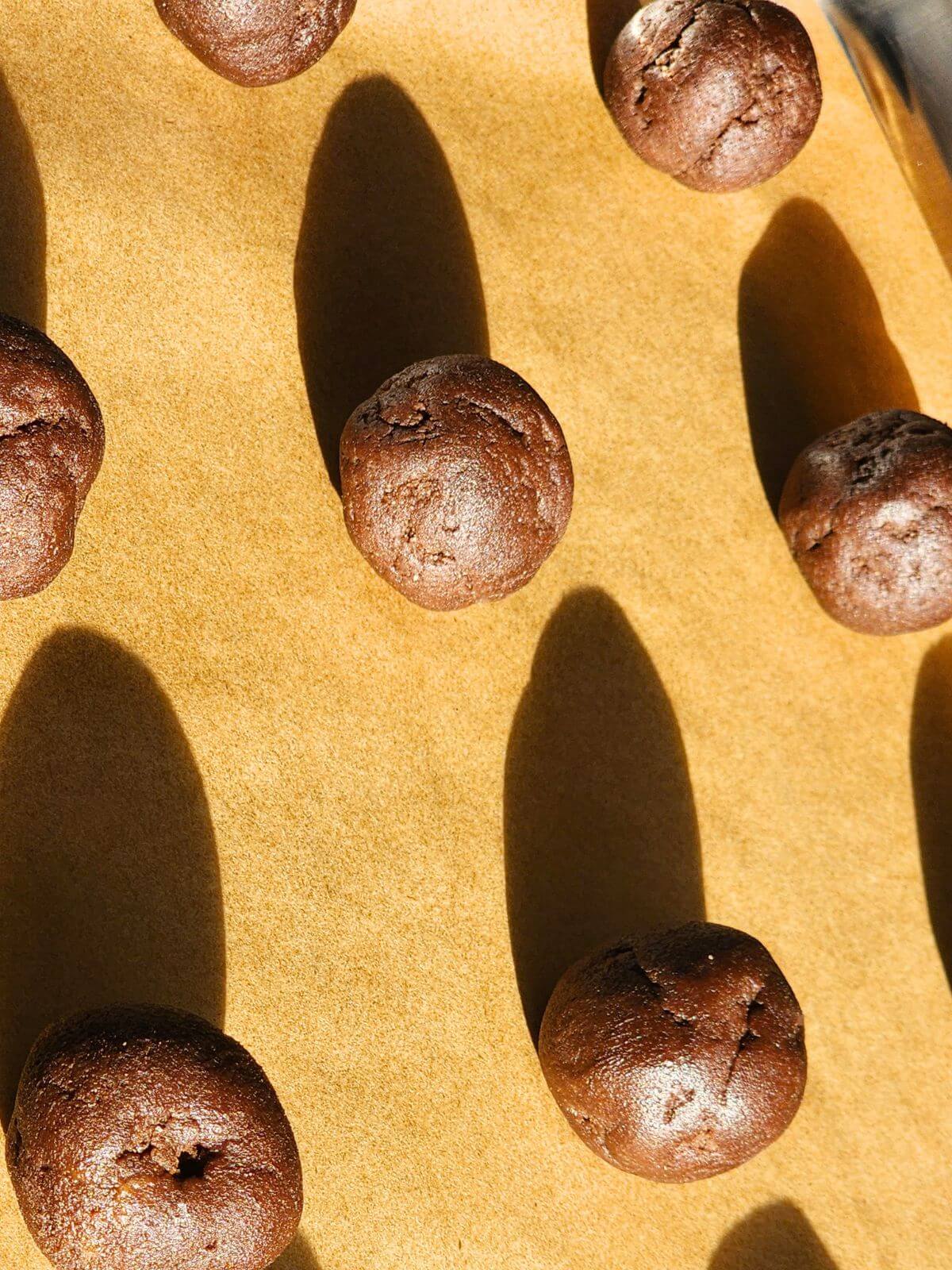 Chocolate sourdough cookie dough balls on parchment paper before baking.