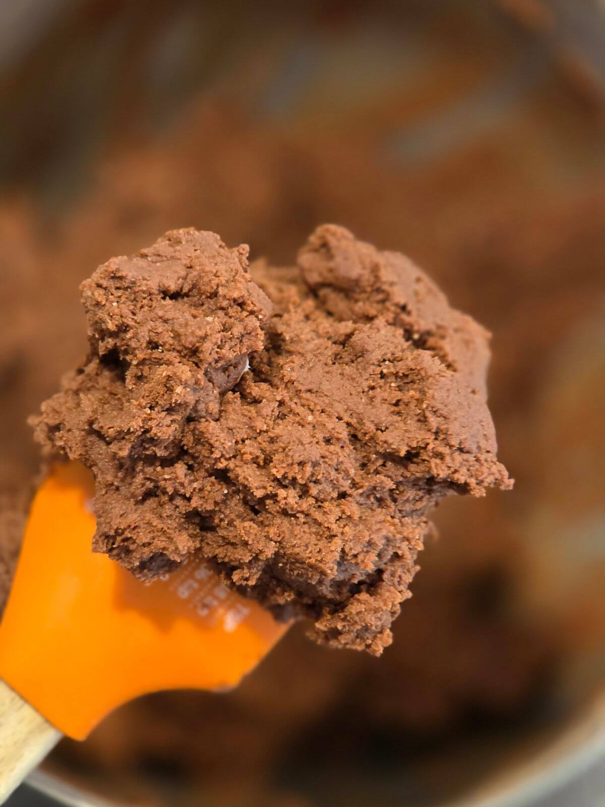 Chocolate sourdough cookie dough on an orange spatula after mixing.