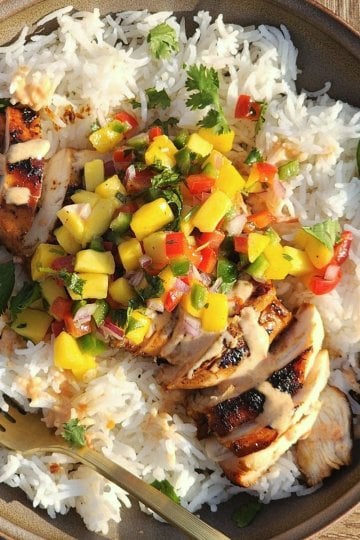 Sweet chili chicken rice bowls with mango salsa, creamy sauce, fresh cilantro, and sliced jalapeños.