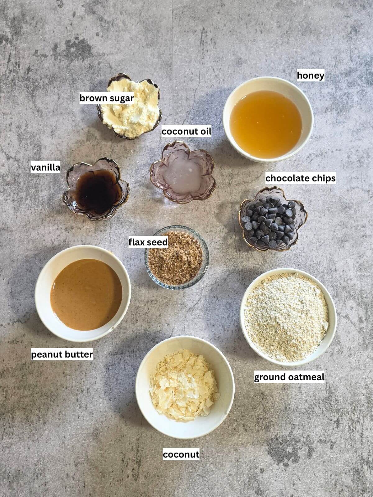 Ingredients for homemade chocolate coconut protein bars, including honey, peanut butter, oats, coconut, flaxseed, protein powder, coconut oil, vanilla, and chocolate chips.