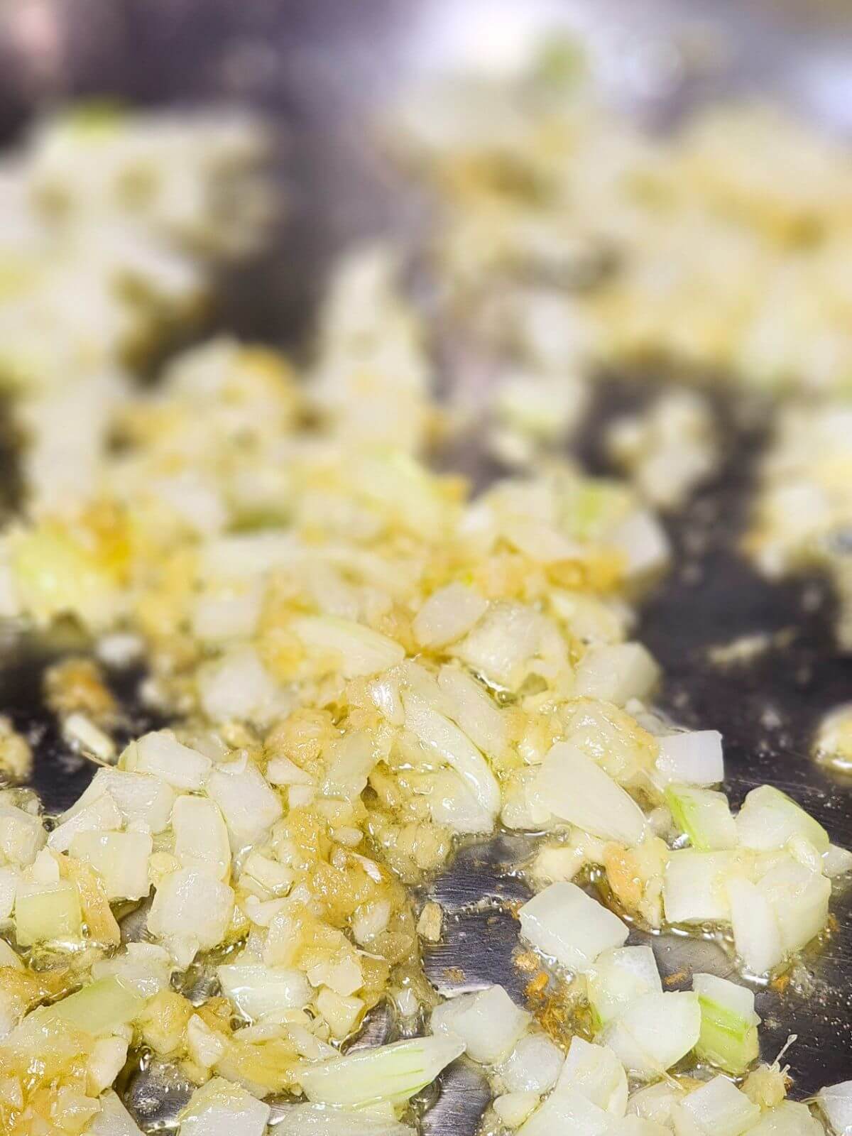 Chopped onion and garlic sautéing in olive oil in a large skillet.
