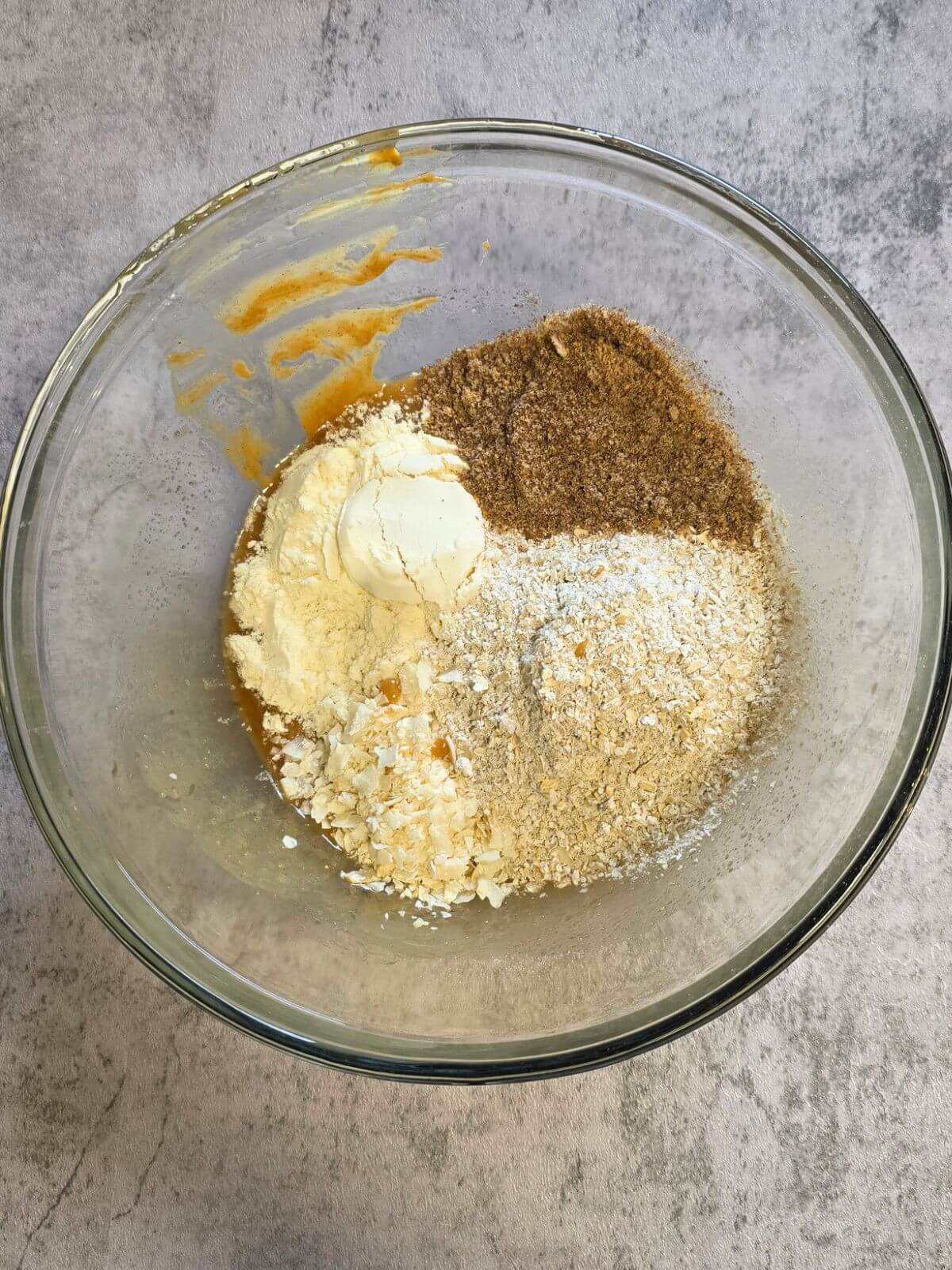 Chocolate coconut protein bar ingredients combined in a glass mixing bowl before stirring.