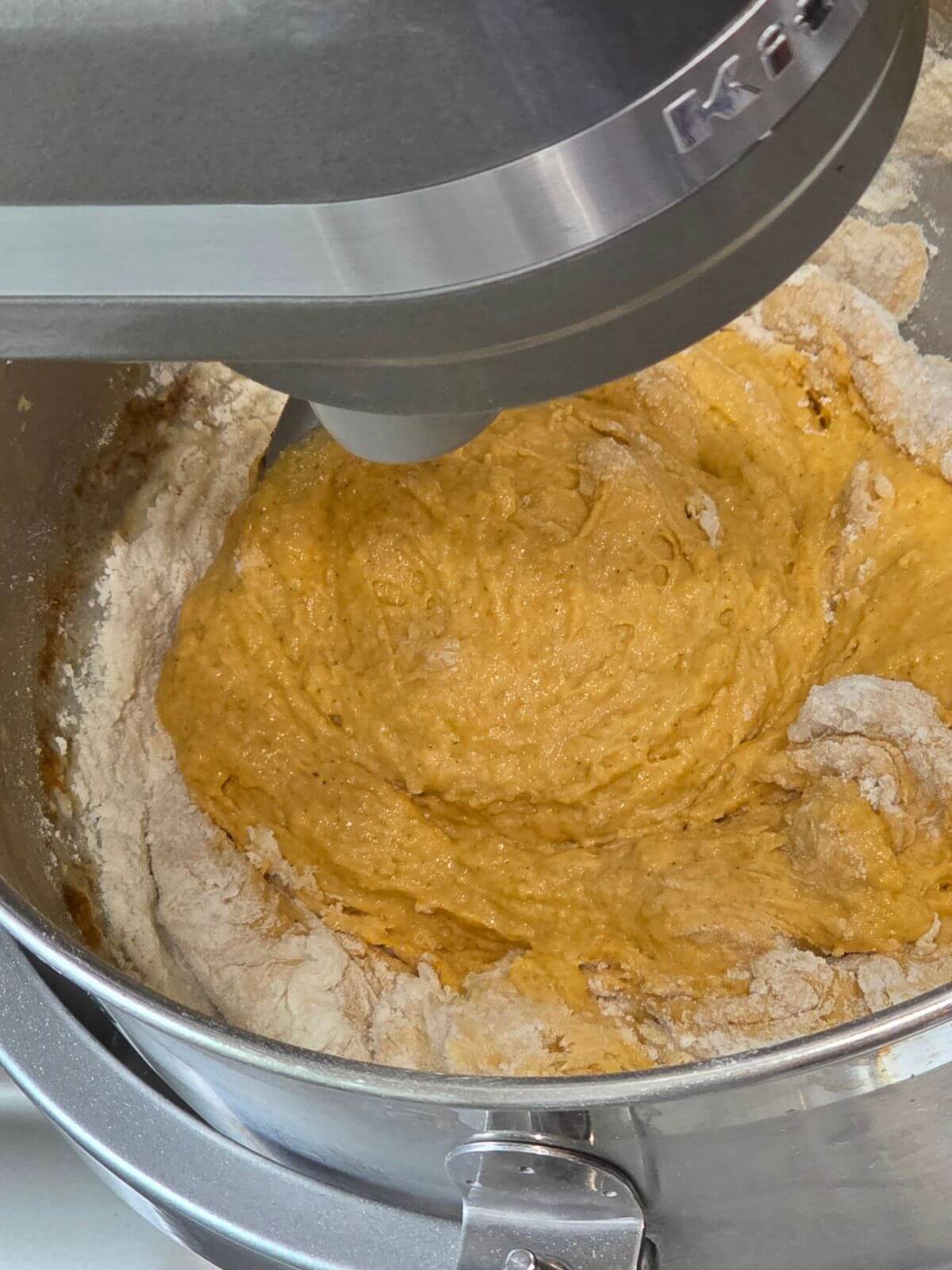 Pumpkin sourdough bagel dough mixing in a stand mixer.