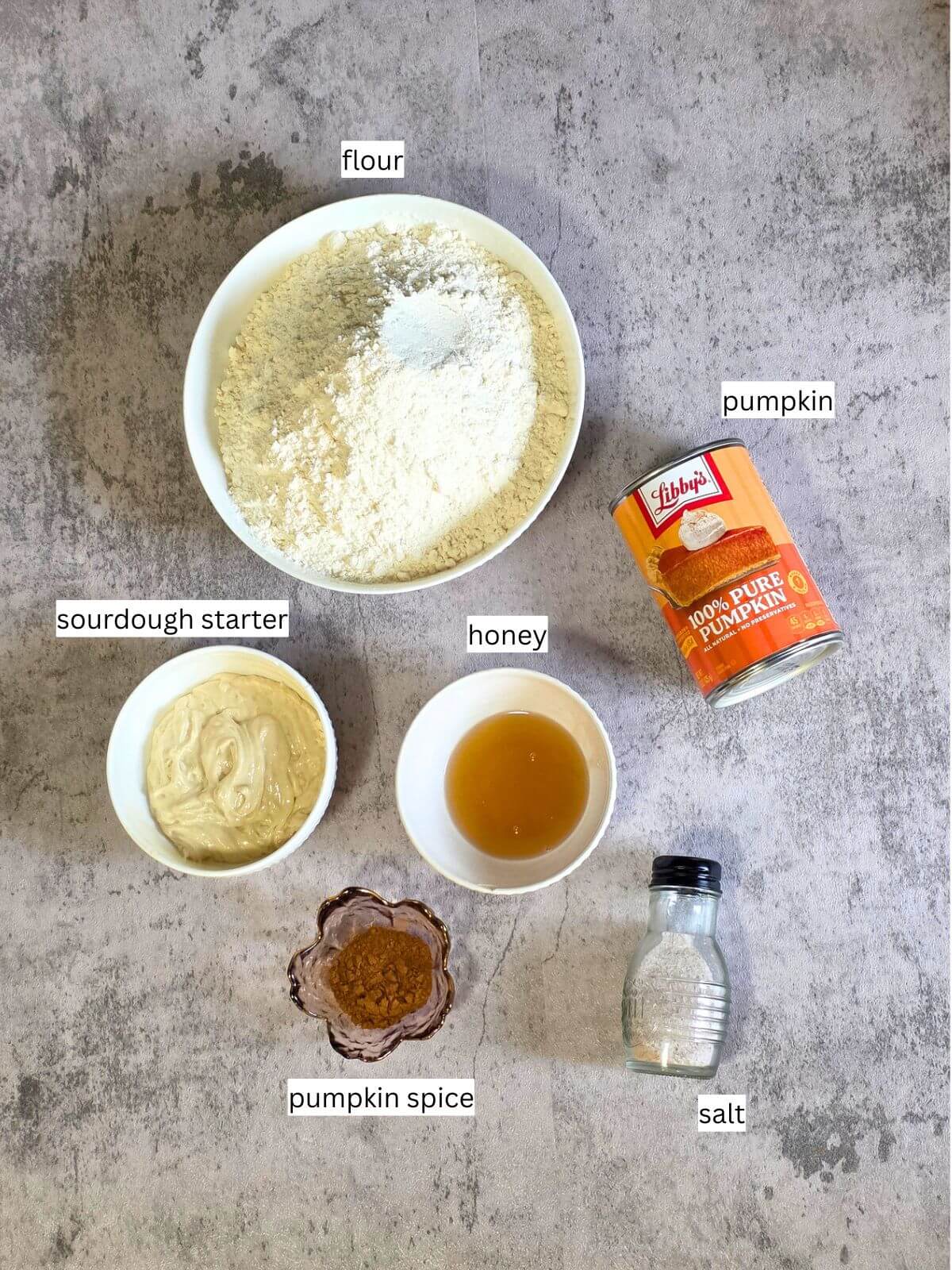 Ingredients for sourdough pumpkin bagels including pumpkin puree, flour, sourdough starter, honey, pumpkin spice, and salt.