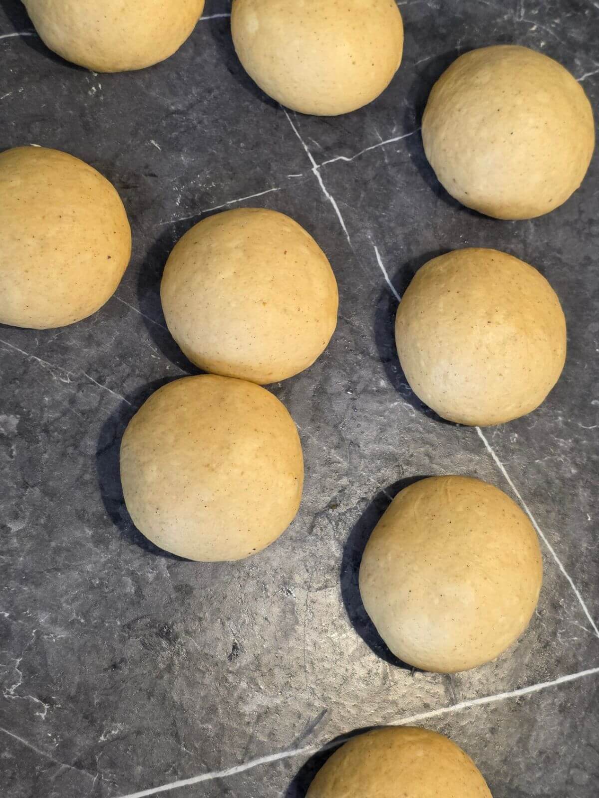 Pumpkin sourdough bagel dough divided and shaped into individual balls.