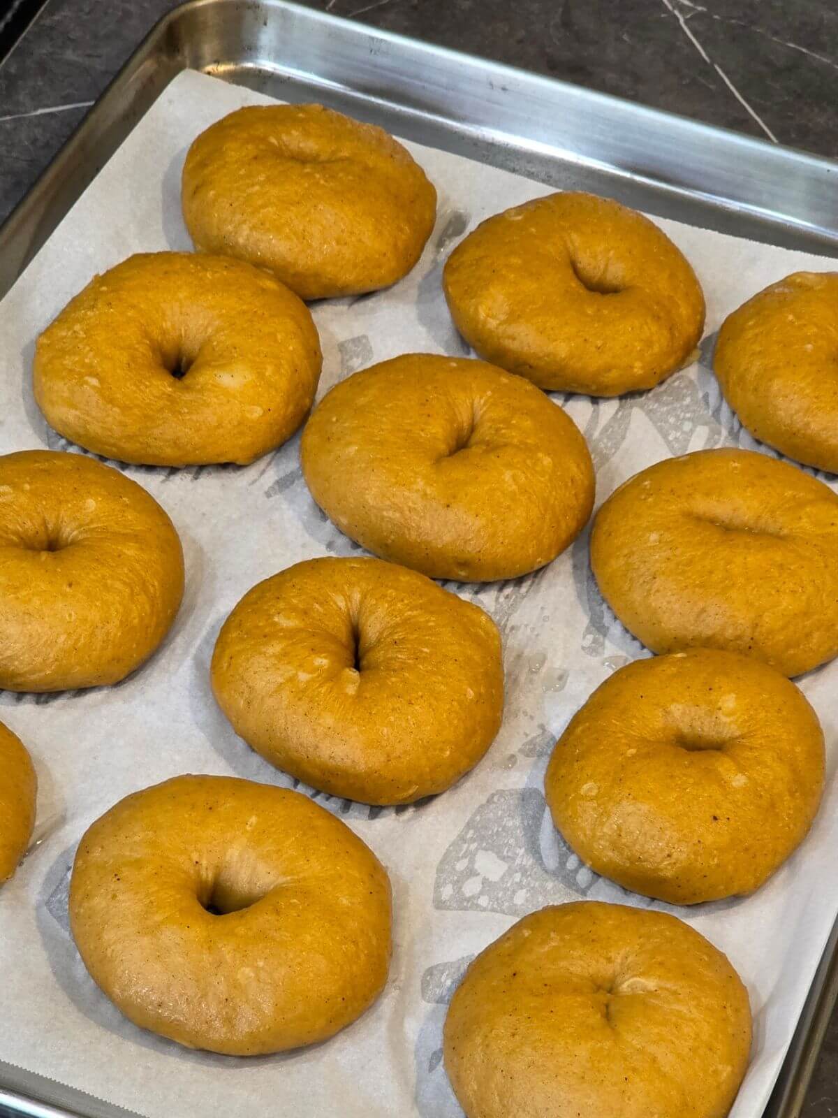 Boiled sourdough pumpkin bagels ready to bake until golden.